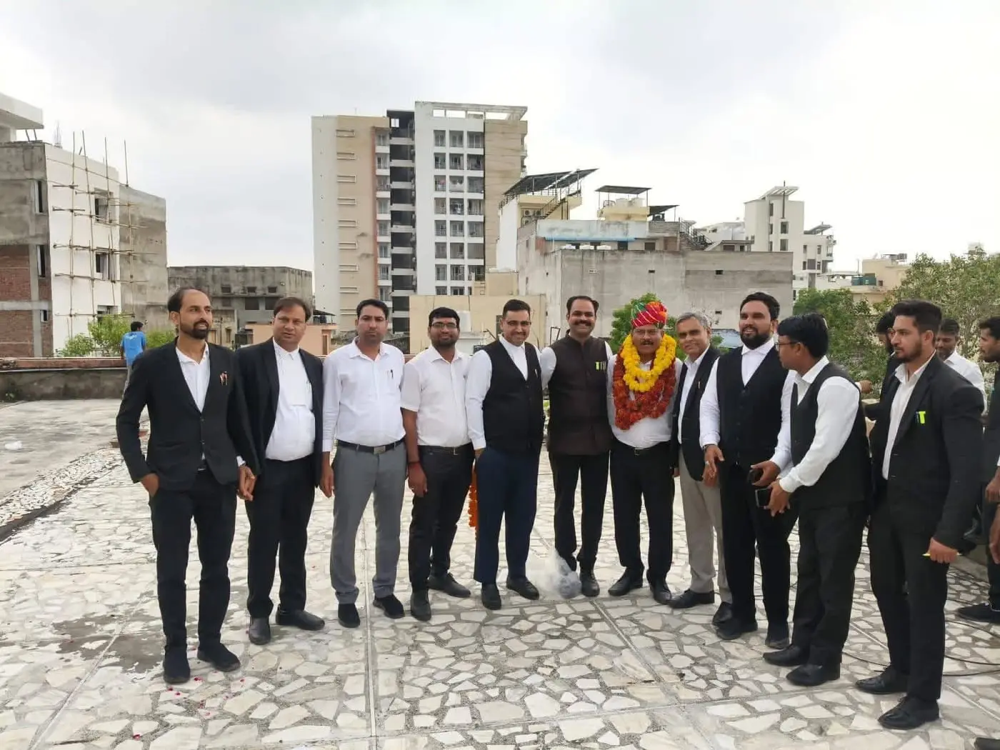 A large group of advocates at a felicitation, with a garlanded member in a Rajasthani turban