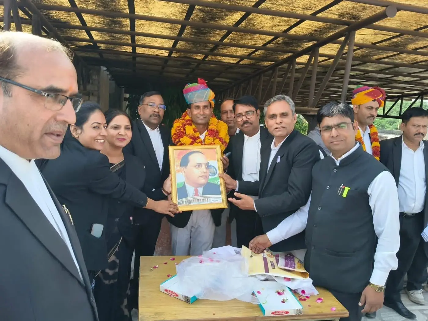 Advocates presenting a framed portrait of Dr B. R. Ambedkar to a garlanded colleague